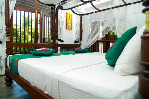 a bedroom with a bed with green and white pillows at Goyambokka Guesthouse in Tangalle