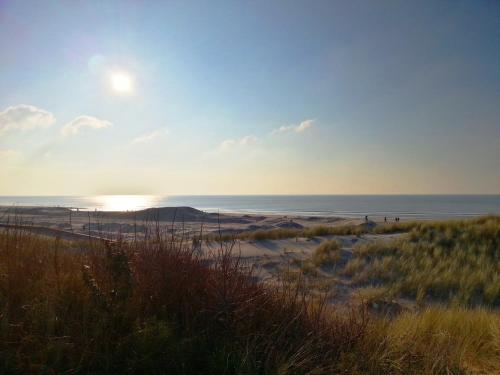 a beach with the sun setting over the ocean at Hôtel Barrière Le Westminster in Le Touquet-Paris-Plage