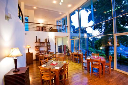 un ristorante con tavoli e sedie in legno e ampie finestre di Hotel See Kandy a Kandy
