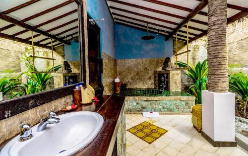 a bathroom with a sink and a fireplace at Hotel Tugu Lombok - CHSE Certified in Tanjung