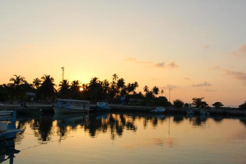 a sunset over a body of water with boats at The Castaway retreat in Feridhoo