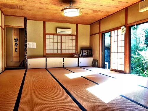 una habitación vacía con una habitación grande con ventanas en 堺のお宿 旧星賀亭, en Kita-noda