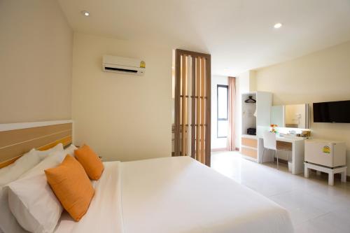 ein weißes Bett mit orangefarbenen Kissen im Schlafzimmer in der Unterkunft Imm Hotel Thaphae Chiang Mai in Chiang Mai