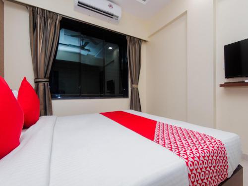 a bedroom with a white bed with red pillows and a window at Hotel Park Inn in Vasai