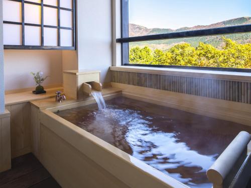 a bathtub with a water fountain in it with a window at Suiun in Hakone