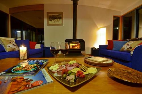 a table with a plate of food and wine glasses at Mures Cloudy Bay Retreat in South Bruny
