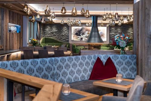 a restaurant with a blue couch and tables and chairs at Alpensporthotel Mutterberg in Mutterbergalm