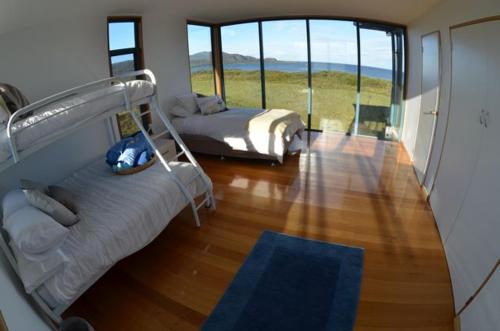 South Bruny的住宿－Mures Cloudy Bay Retreat，一间卧室设有两张床和大窗户