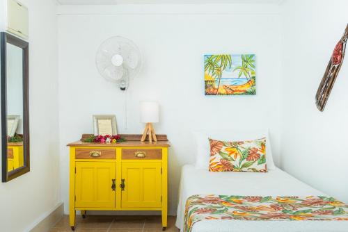 a bedroom with a yellow nightstand next to a bed at The Cooks Oasis in Rarotonga