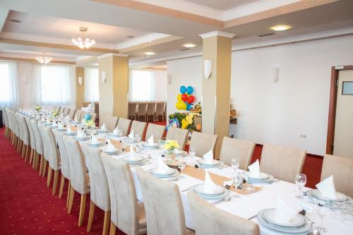 a long table with white tables and chairs in a room at Hotel CITY in Prnjavor