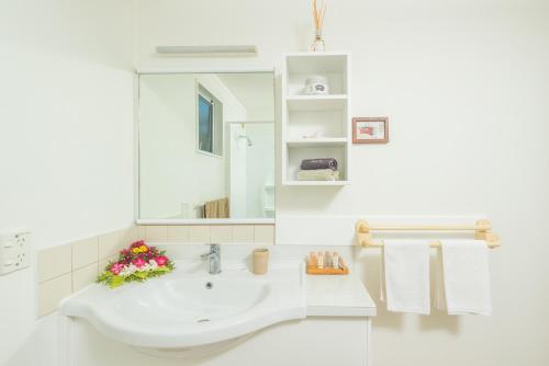 a white bathroom with a sink and a mirror at The Cooks Oasis in Rarotonga