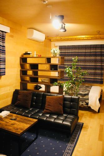 a living room with a black leather couch and a table at Alo BnB 1 - Near UENO, AKIHABARA, SENSOJI, TOKYO SKY TREE - Self check-in in Tokyo