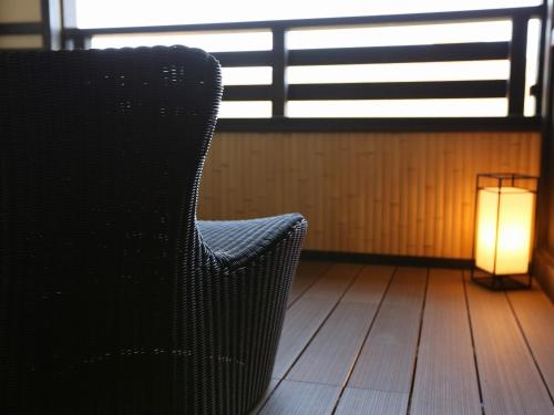 a black chair and a lamp on a wooden floor at Suiun in Hakone