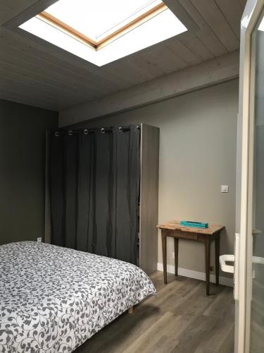 - une chambre avec un lit, une table et une lucarne dans l'établissement Les Terrasses de La Malcombe, à Besançon