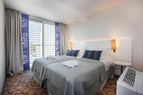 ein Hotelzimmer mit 2 Betten und einem Fenster in der Unterkunft Amadria Park Ivan in Šibenik