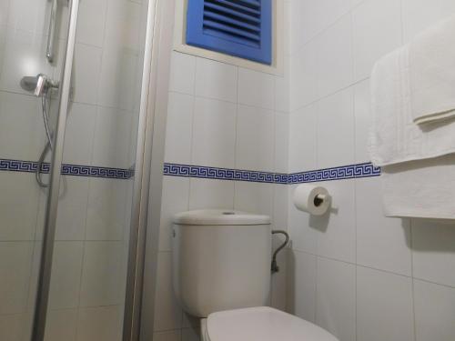a white bathroom with a toilet and a shower at Hotel Caleta in Lloret de Mar