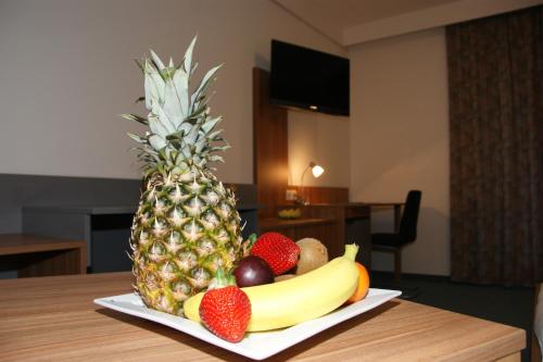 a plate of fruit on a table with a pineapple at Dolomitenhotel Lienz in Lienz