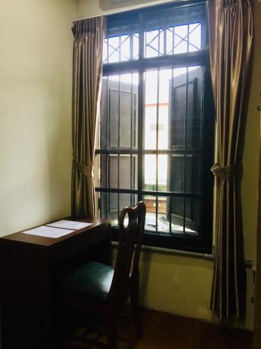 a room with a desk and a window with a chair at Phuket Sunny Hostel in Phuket Town