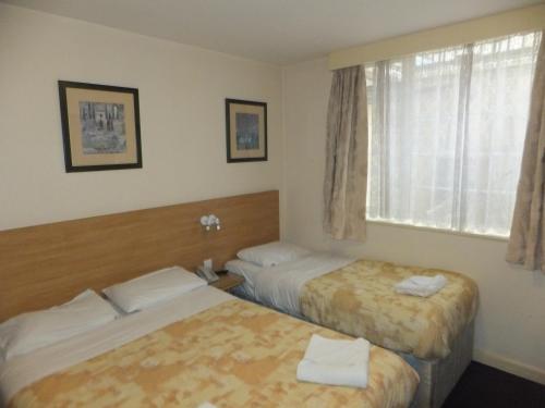 a hotel room with two beds and a window at Colliers Hotel in London