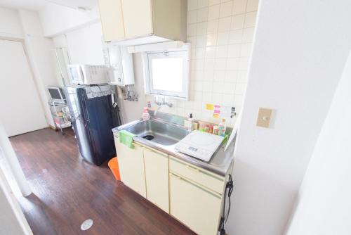 a small kitchen with a sink and a refrigerator at Luxes Hiroshima4F ラクセス ヒロシマ4F in Hiroshima