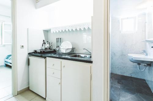 cocina blanca con fregadero y encimera en Panorama Apartments updated with infinity pool, en Agios Nikolaos