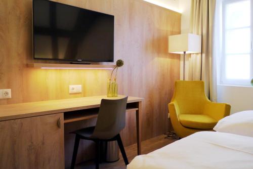 a hotel room with a desk with a television on a wall at Das Brunners in Weiden