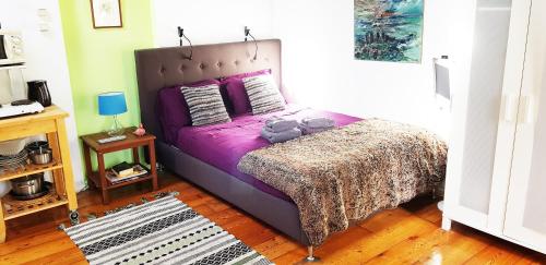 a bedroom with a bed with purple sheets and pillows at Romantic quiet studio on the canal in Amsterdam