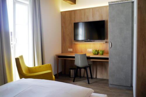 a hotel room with a desk and a tv at Das Brunners in Weiden