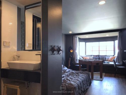 a bathroom with a tub and a sink and a living room at Stay in Style at Nimman R911 in Chiang Mai