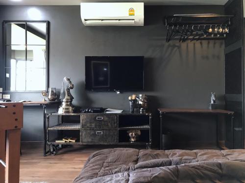 a bedroom with a bed and a tv on a wall at Stay in Style at Nimman R911 in Chiang Mai