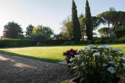un giardino fiorito e un prato alberato di Borgo Villa Risi a Siena
