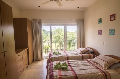 1 dormitorio con 2 camas y ventana con balcón en Acqua Residences 503, en Jacó
