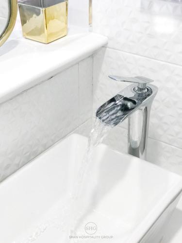 a bathroom sink with water running from a faucet at Stay in Style at Nimman R912 in Chiang Mai