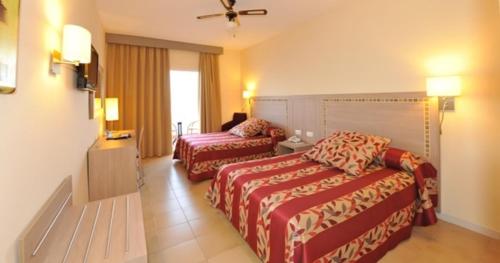 a hotel room with two beds and a television at Hotel Salobreña Suites in Salobreña