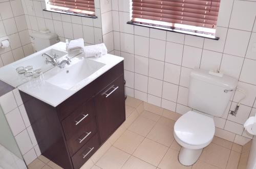 a white bathroom with a sink and a toilet at The Nest Drakensberg Mountain Resort Hotel in Champagne Valley