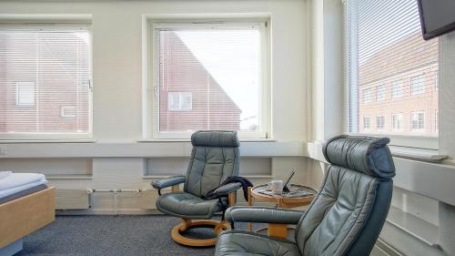 two chairs and a table in a room with two windows at BB-Hotel Rønne Bornholm in Rønne