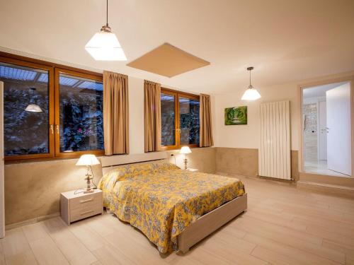 a bedroom with a bed and two lamps and windows at Belvilla by OYO Villa Meraviglia in Artogne
