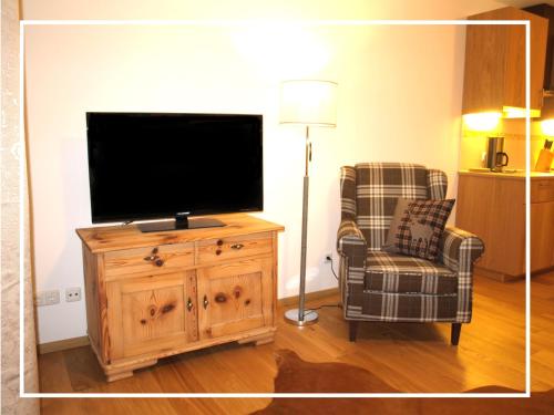 a living room with a flat screen tv and a chair at Kaiserapart Steinadler - ELLMAU Zentrum in Ellmau