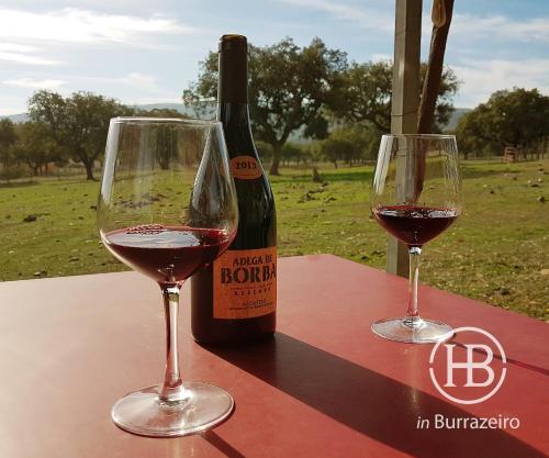 two glasses of red wine next to a bottle of wine at Herdade do Burrazeiro in Borba