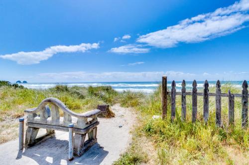 a bench sitting on the beach near a fence at M & M Beach Nest in Rockaway Beach