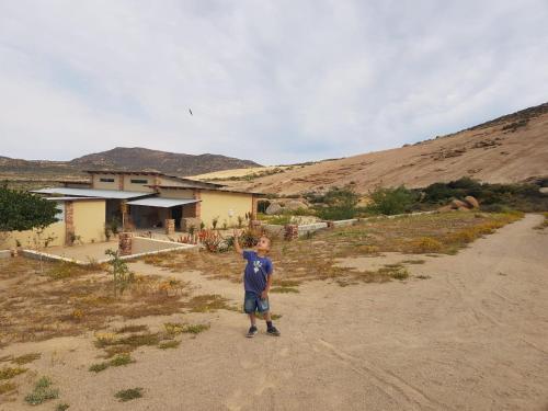 a young boy standing in front of a house at Jakkalswater guest farm in Nababeep