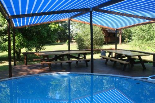 a group of picnic tables under a blue roof at Ma's Cottage in Sodwana Bay