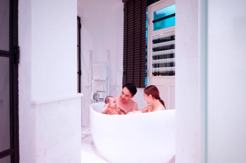 a man and a woman holding a baby in a bathtub at Hotel NuVe Urbane in Singapore