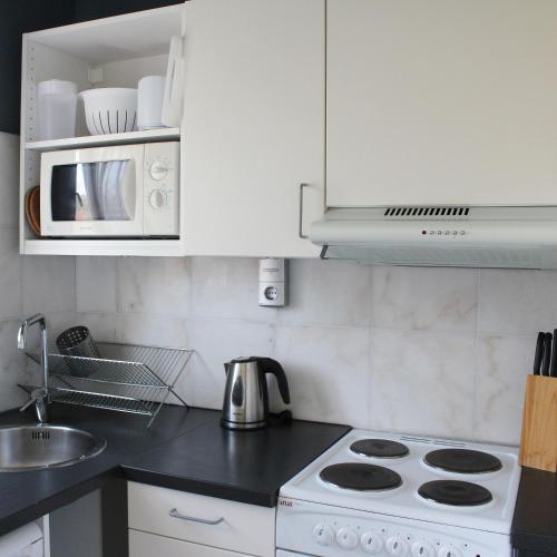 a white kitchen with a stove and a microwave at Place Lund Studios in Lund