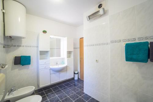 a white bathroom with a sink and a toilet at Apartment Jadranka in Brist