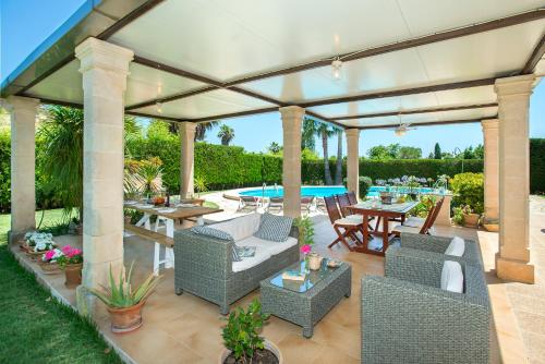 um pavilhão com cadeiras, uma mesa e uma piscina em Owl Booking Villa Coloma - Luxury Retreat with Huge Pool em Port de Pollensa