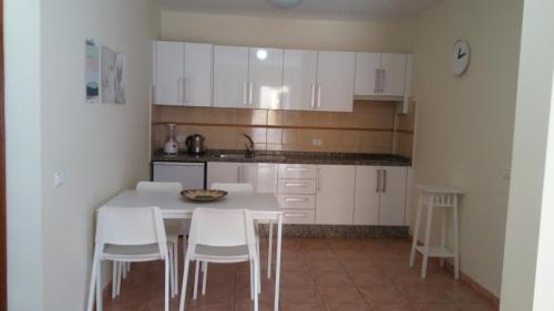 La Playa CaleraにあるAPARTAMENTOS EL CIENOの白いキャビネット、テーブルと椅子付きのキッチンが備わります。