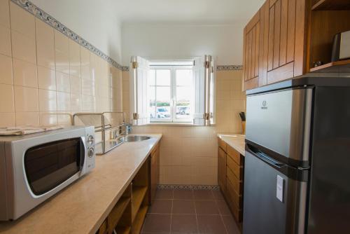 a kitchen with a microwave and a refrigerator at Villa Eira in Vila Nova de Milfontes