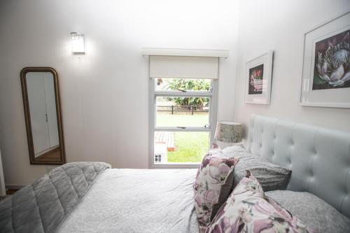 a bedroom with a bed and a mirror and a window at Valmont Estate in Plettenberg Bay