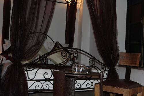 a bed with curtains and a table and a chair at Riad Terra Bahia in Marrakech